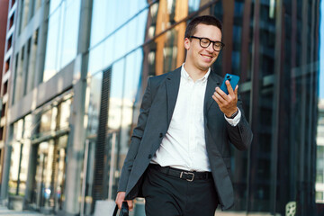 Business professional enjoys a sunny morning in the city while checking his phone and walking...