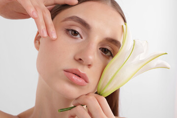 Portrait of attractive young woman with flower on white background