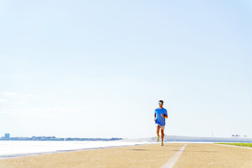 Running along the waterfront under a bright blue sky during a sunny afternoon in a vibrant city park