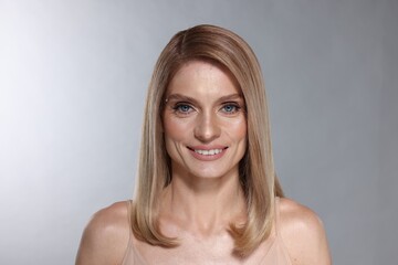 Fototapeta premium Portrait of beautiful happy woman with straight blonde hair on light grey background