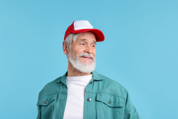 Elderly man in stylish outfit on light blue background