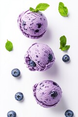 three blueberry ice cream scoops with fresh mint leaves on a white surface, ideal for summer ads, dessert menus, recipe blogs, and food packaging