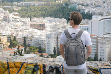 A man tourist with a backpack looks at the panorama of the city of Athens from the observation...