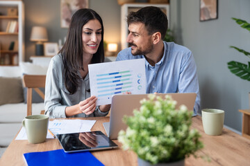 Young intelligent innovative hipster couple presenting their startup new business idea via video call on laptop computer, working at home, talking to potential investor. Modern technology innovation.