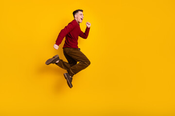 Young Man Jumping Energetically Against Yellow Background in Fashionable Casual Outfit