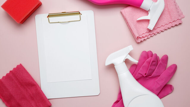 Mock up clipboard. Household cleaning and hygiene concept. Pink cleaning supplies including rubber gloves, spray bottle, microfiber cloths