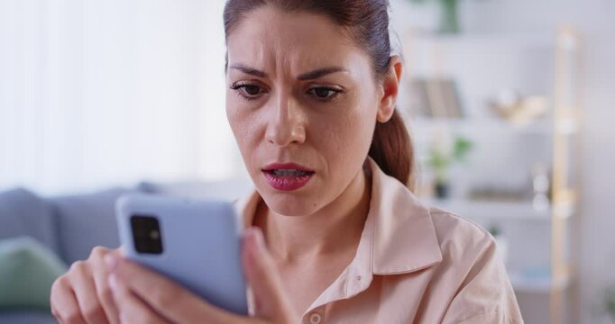 Sad woman at home uses phone for online leisure and receives bad news on the internet. Emotional impact of negative messages and the connection between mobile technology and everyday life.