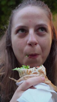 A female foodie tries a freshly made vegan falafel duner from a small street cart during her walk through Sofia