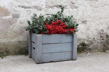 Rustic wooden crate overflowing with holly berries, invoking Yuletide nostalgia and celebrating the Winter Solstice's vibrant renewal