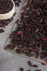 Dried mulberries on a drying rack on marble table