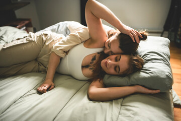 Happy couple cuddling on their bed at home. Romantic young LGBTQ+ couple together in their bedroom....