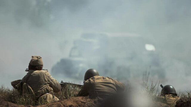 Red Army Soviet soldiers on defensive position firing from trench German troops, Wehrmacht offensive, Great Patriotic War battle simulation. WWII reenactment. Smoke fills air. Military truck vehicle