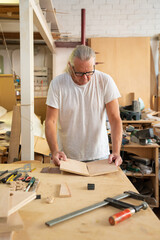 Carpenter working on wood craft at workshop.