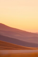 Naklejka premium Serene desert landscape at sunset, showcasing rolling hills and a tranquil road. Evokes feelings of peace, adventure, and the beauty of nature.