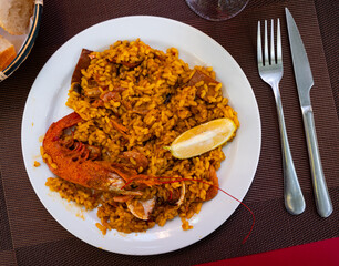 Paella made of rice and different seafood served in plate with other table appointments
