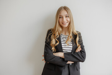 Confident young woman in a professional outfit poses in a modern office environment with a warm...