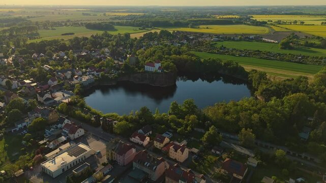 Drone clip of the Wehrkirche Beucha in Saxony, Germany. Perched on a rocky cliff above a former quarry lake, the church is illuminated by soft evening light and surrounded by peaceful countryside.