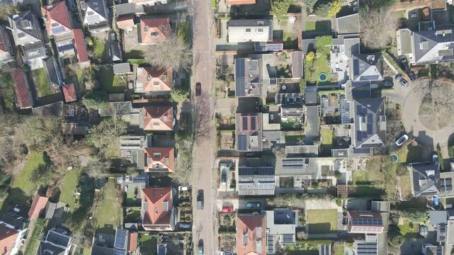 Top down aerial of a wealthy neighborhood with photovoltaic solar panels on the rooftops in a small town in the Netherlands on a sunny day