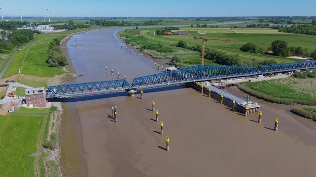 Wide aerial view of the Friesenbr&uuml;cke across the Ems River in Northern Germany. The modern lift-swing railway bridge appears closed, showing its structural length and construction details.