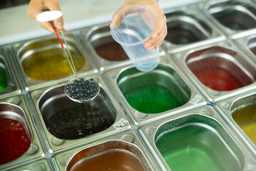 Cropped shot of barista preparing bubble tea, adding black pearls from stainless steel container...