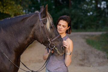 beautiful girl with horse walking in park in summer. equestrian sport