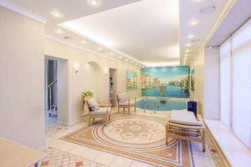 Indoor pool room with Venetian-themed wall mural, tiled floor, two armchairs, and a lounge chair. Elegant and serene