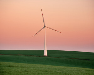 Obraz premium Wind turbine farm in a green field generating renewable energy under a clear blue sky