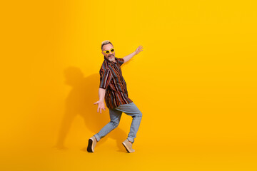 Middle aged bearded man in casual vibrant attire posing against yellow background with enthusiastic...
