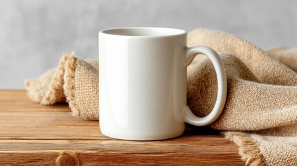 A white ceramic mug rests on a wooden surface with a soft, beige blanket, creating a warm and cozy scene. 