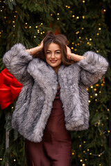 Beautiful Caucasian girl on the street in winter in a fur coat celebrates Christmas and New Year.
