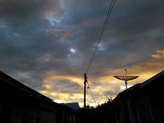 The view of the sunset with the golden yellow sky from above the housing reflects a very beautiful...