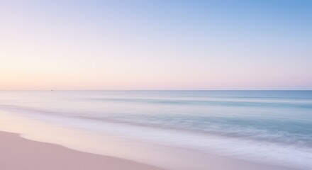 Obraz premium Soft pastel colors over calm ocean water and sandy beach at sunrise