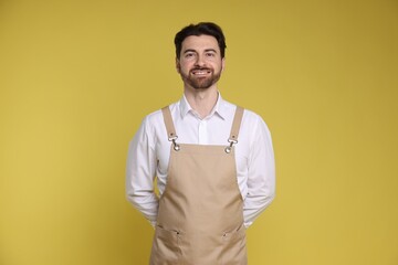 Portrait of smiling barista on yellow background