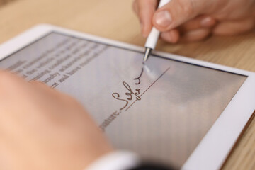 Electronic signature. Man using stylus and tablet at table, closeup