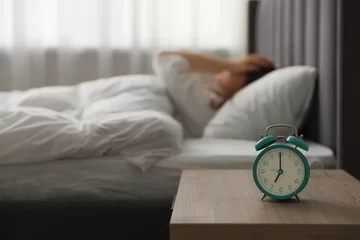 Fotobehang Upset young woman on bed at home, focus on alarm clock © New Africa