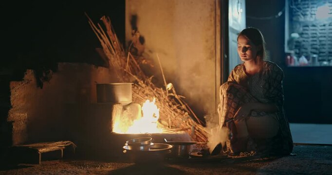 Indian gen z young villager woman preparing food using traditional earthen mud stove indoor house Asian teen age female cooking on open fire flam inside kitchen home	