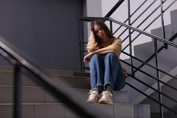 Bullying. Upset teenage girl on stairs indoors