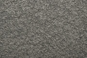 Fototapeta premium Close-up of rough gray granite surface texture. Ideal for backgrounds, architectural visuals, or material samples in design projects.