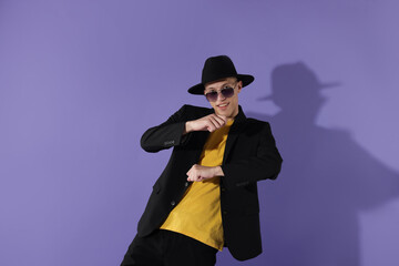 Happy man in sunglasses dancing on violet background