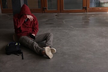 Homeless man sitting on city street. Space for text