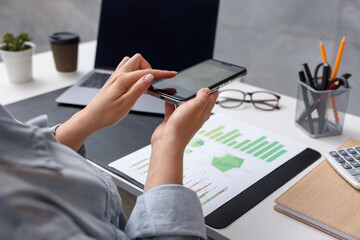 Woman taking photo of document using scanning app on smartphone at desk in office, closeup