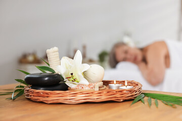 Senior woman relaxing on massage couch indoors, focus on different spa products and lily flower