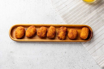 Breaded ham croquettes aligning on wooden tray: delicious spanish tapas