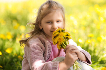 Cute little girl with beautiful dandelions outdoors on sunny day