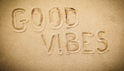 Words 'Good Vibes' written in Soft Beach Sand – Summer Fun and Vacation Symbol. Sand background with copy space..