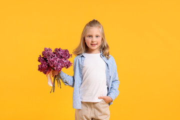Little girl with bouquet of lilac flowers on yellow background