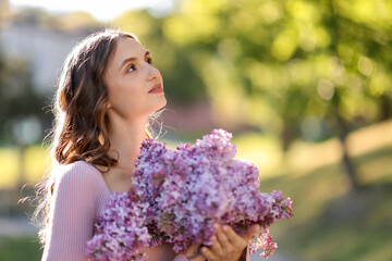 Fototapeta premium Beautiful woman with bouquet of lilac flowers outdoors in morning