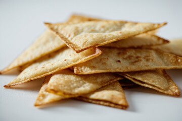 Fototapeta premium A pile of crispy pita chips served on a clean white plate, ready for snacking or serving with your favorite dips and spreads