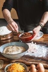 Hands skillfully measure and mix ingredients, showcasing the tactile joy of baking. The warm wooden...