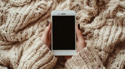 Woman holding phone on a knitted blanket